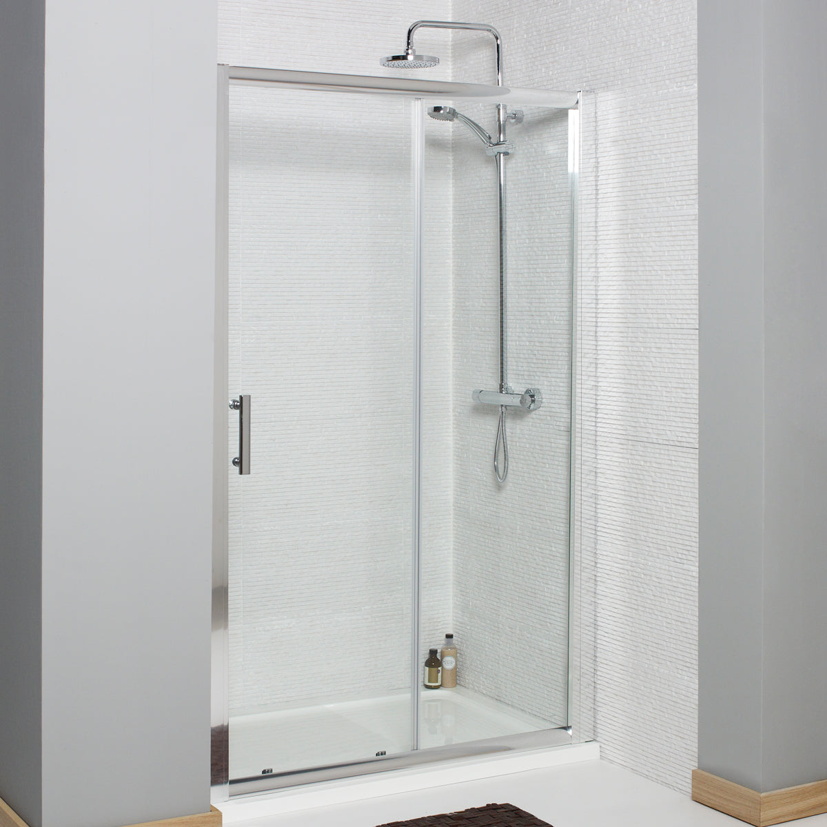 Modern glass shower enclosure with chrome rainfall shower head and white tile walls