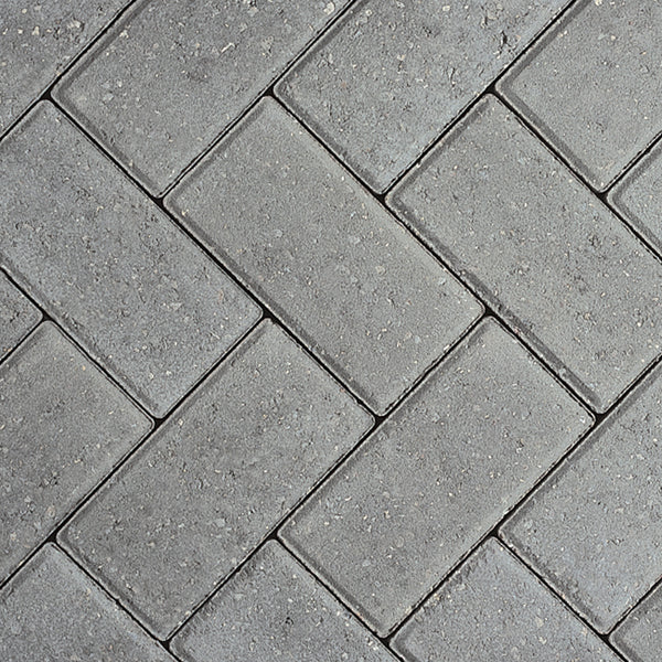 Grey concrete paving blocks arranged in a herringbone driveway pattern