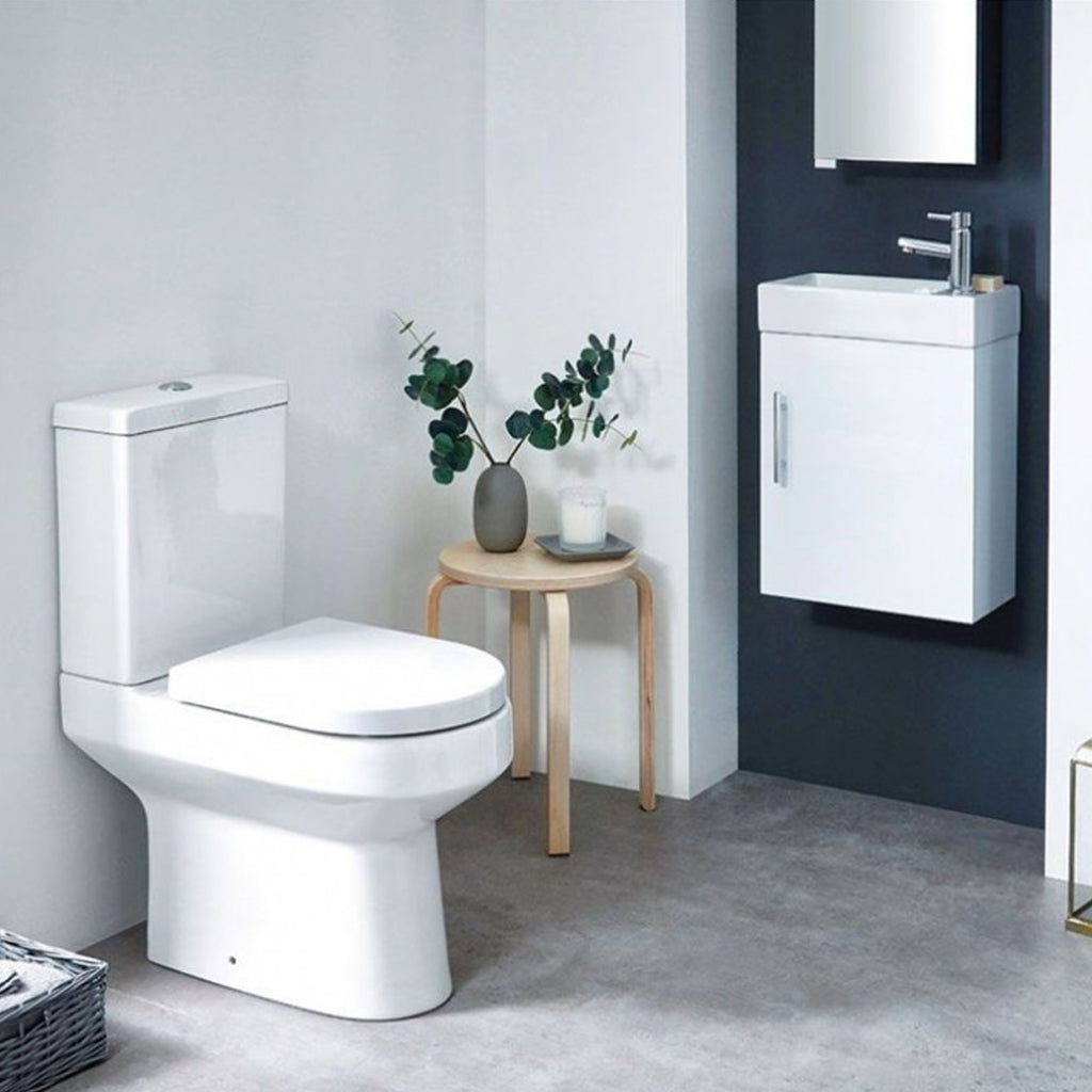 Modern white bathroom suite with toilet, compact vanity unit and small round side table