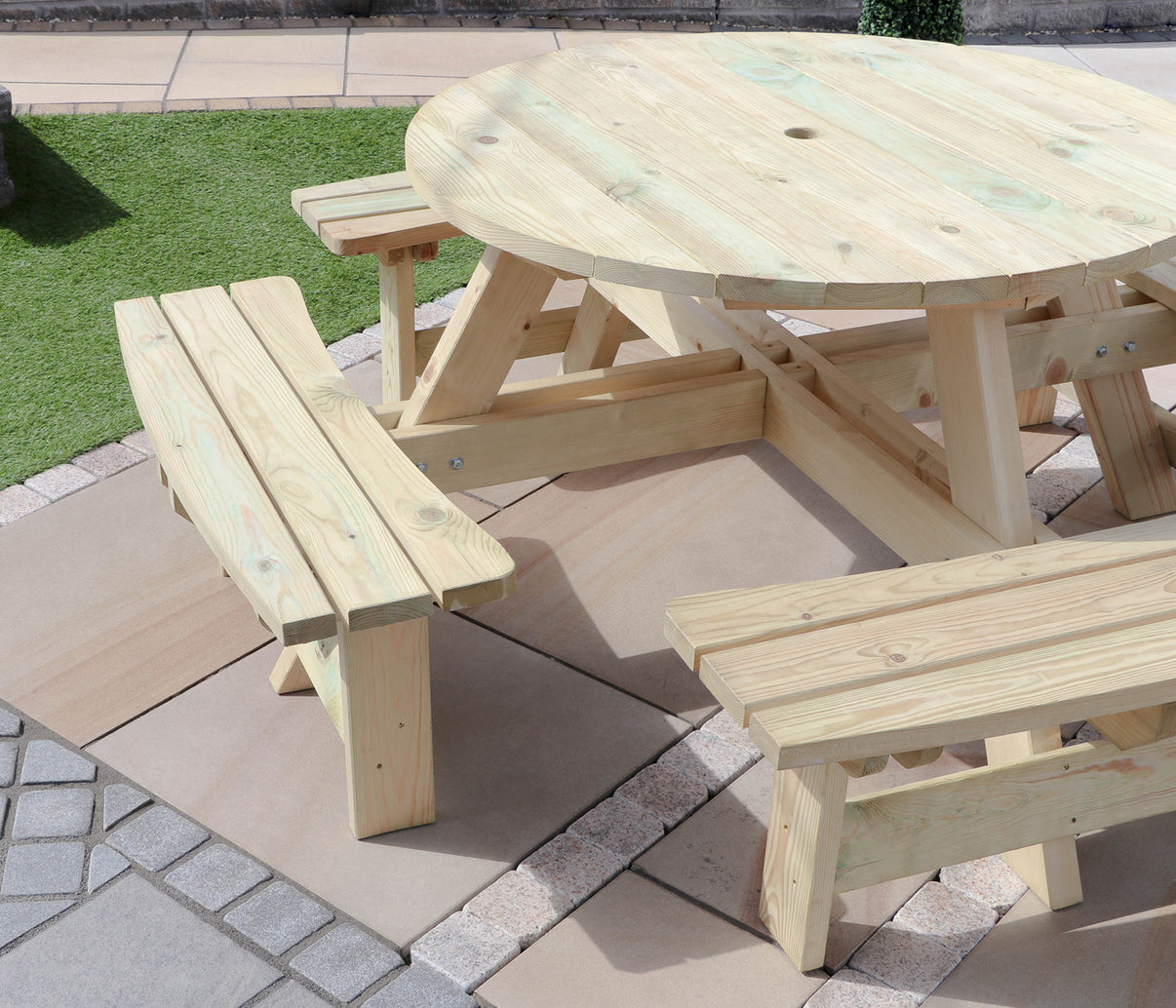 Round wooden picnic bench with attached seats on patio paving outdoors