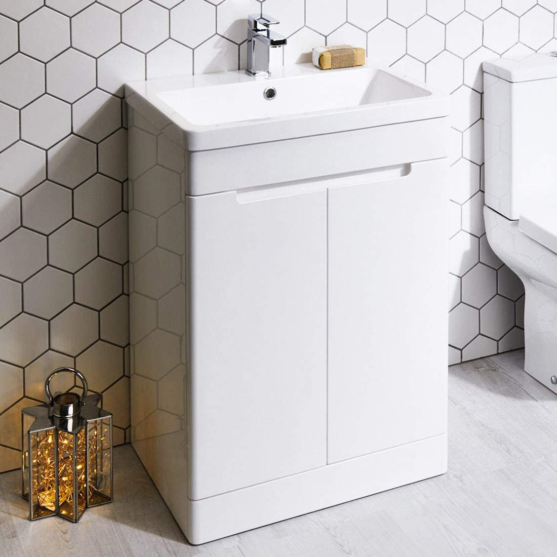 Modern white bathroom vanity unit with integrated sink and chrome tap against hexagon tile wall