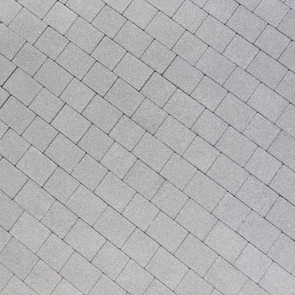 Grey concrete paving blocks arranged in a herringbone pattern, outdoor surface