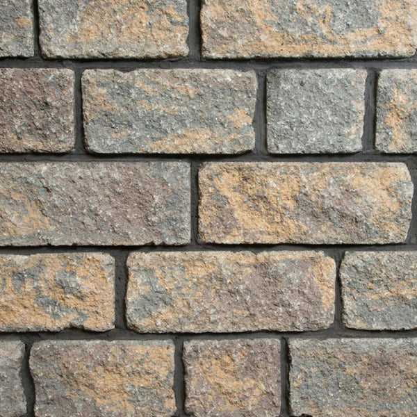 Close-up of textured stone wall blocks in mixed grey and tan for building materials