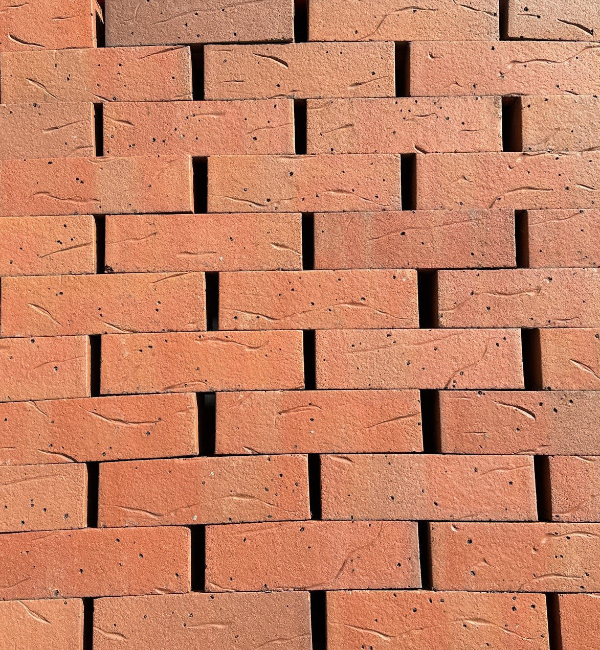 Red clay bricks stacked in a staggered pattern for construction or building materials
