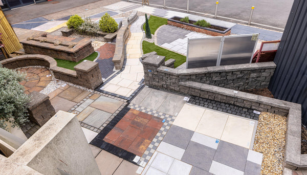 Outdoor landscaping display with various paving slabs, block paving, stone walls, and gravel
