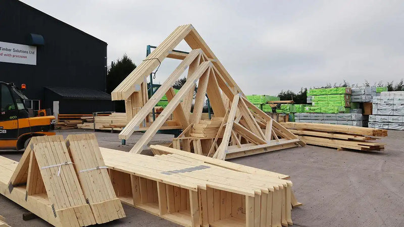 Timber roof trusses and wooden building materials stacked at outdoor construction supply yard