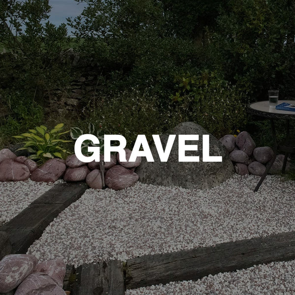 Decorative garden with white gravel, large rocks, landscaping timbers, and green plants